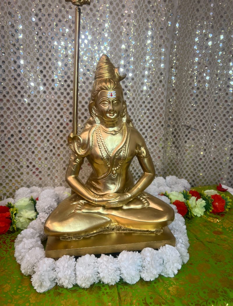 A gold statue of a woman sitting in the middle of a flower wreath.