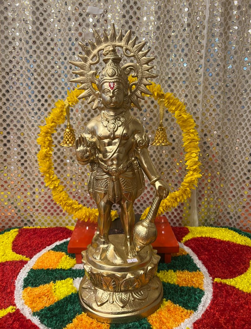A statue of an indian god is sitting on the ground.