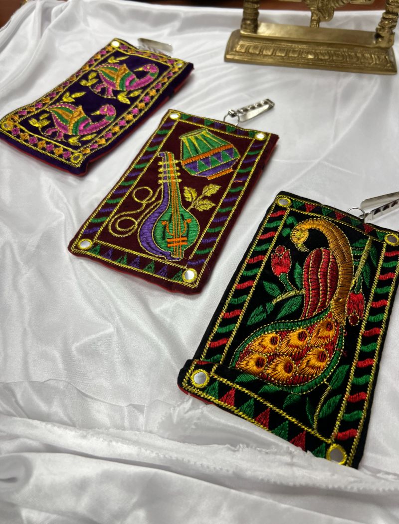 Three colorful wallets sitting on a bed.