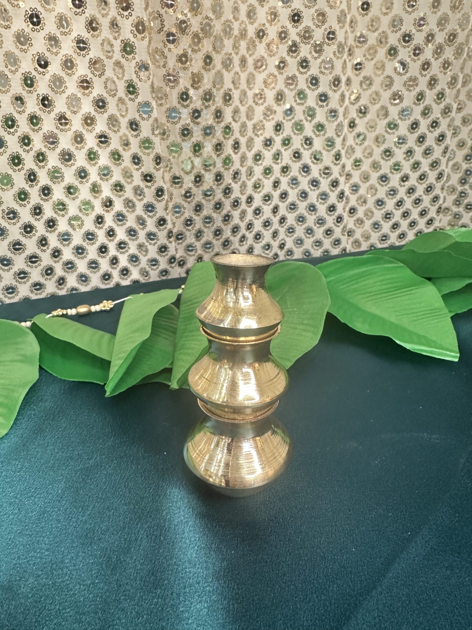 A small brass vase sitting on top of a table.