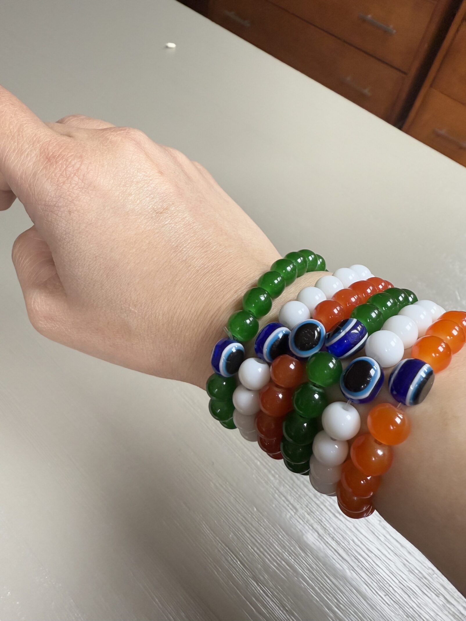 A hand is holding some bracelets with evil eye beads.